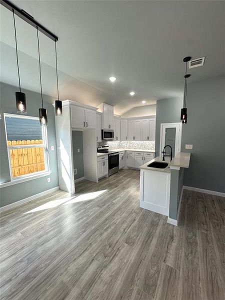 Kitchen with white cabinetry, appliances with stainless steel finishes, sink, and pendant lighting