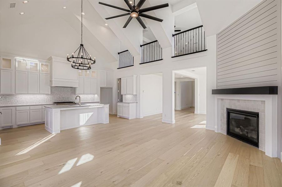 Kitchen featuring open floor plan, high vaulted ceiling, decorative backsplash, white cabinets, and glass insert cabinets Kitchen featuring open floor plan, high vaulted ceiling, decorative backsplash, white cabinets, and glass insert cabinets