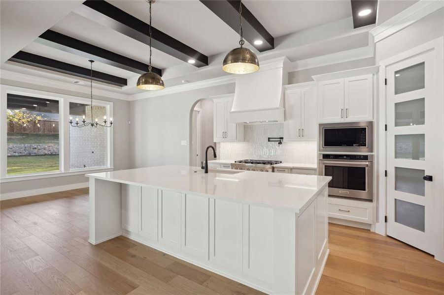 Kitchen featuring beam ceiling, white cabinetry, sink, stainless steel appliances, and custom exhaust hood