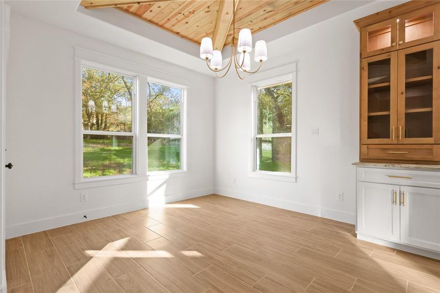 Unfurnished dining area with wood finish floors, wooden ceiling, and a chandelier