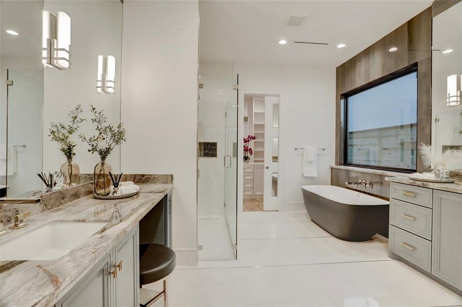 PRIMARY BATH: Incredibly inviting en-suite with inlaid polish silver details in the flooring and mixed finishes, a feature wall of dramatic porcelain highlights the freestanding tub with the black exterior, and oversized, walk-in shower with double showerhead and handhelds.  Sequestered WC and please note the brass and polish nickel hardware and plumbing selections.