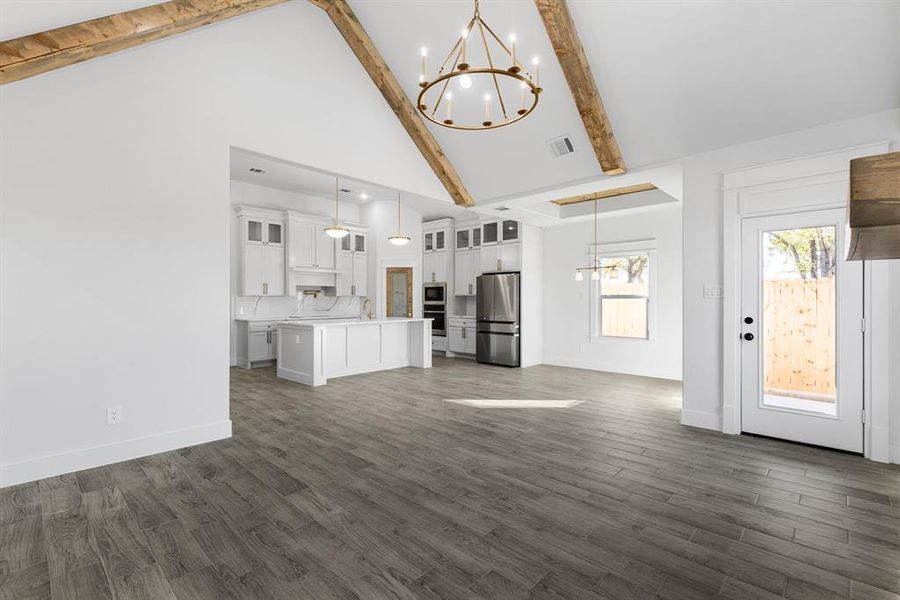 Unfurnished living room with beamed ceiling, dark hardwood / wood-style flooring, high vaulted ceiling, and sink