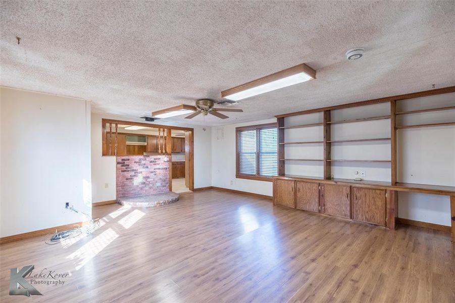 Unfurnished living room with a textured ceiling, light wood-type flooring, and a ceiling fan Unfurnished living room with a textured ceiling, light wood-type flooring, and a ceiling fan