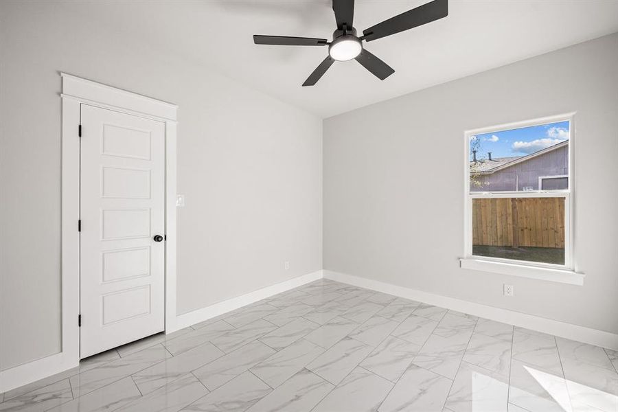 Empty room with light marble finish flooring and a ceiling fan