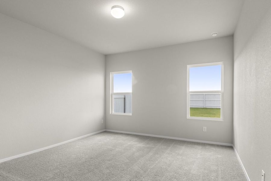 Image of primary bedroom with light grey carpeting and painted walls with two windows