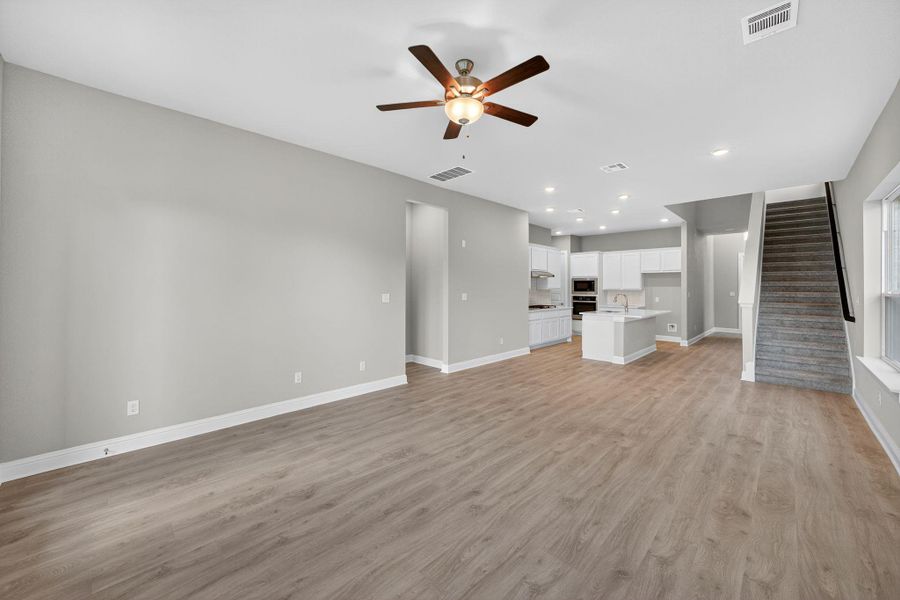 Unfurnished living room with light wood-style floors, stairs, ceiling fan, and recessed lighting Unfurnished living room with light wood-style floors, stairs, ceiling fan, and recessed lighting
