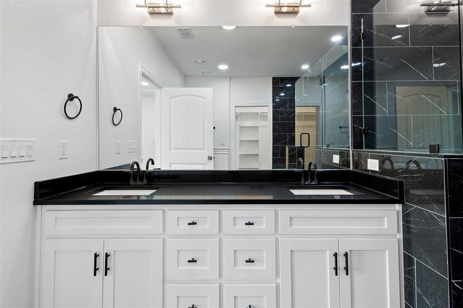 Full bathroom with double vanity, a stall shower, recessed lighting, and a closet