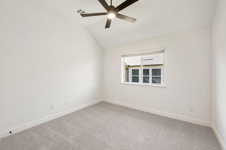 Empty bedroom with vaulted ceiling, ceiling fan, carpet flooring, and single window Empty bedroom with vaulted ceiling, ceiling fan, carpet flooring, and single window