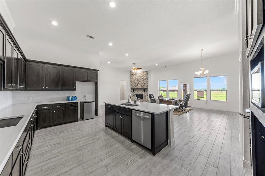 Kitchen featuring a sink, dishwasher, open floor plan, a fireplace, and light countertops