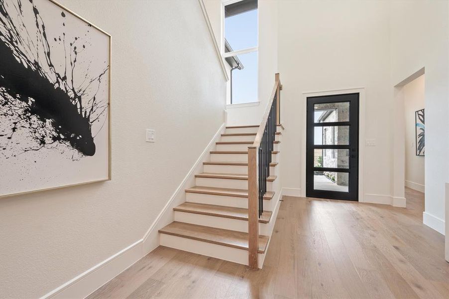 Entrance foyer with light wood-type flooring and a high ceiling