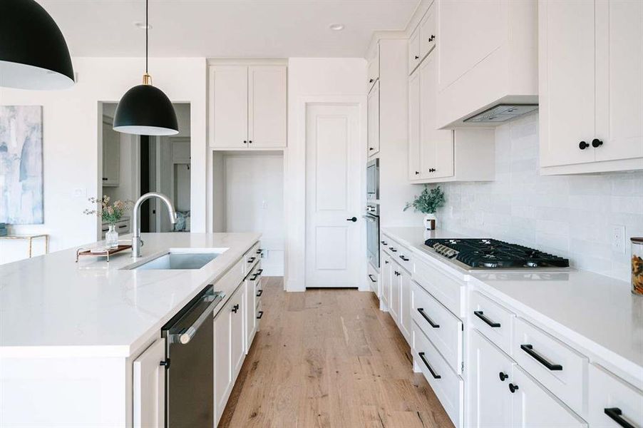 Kitchen featuring white cabinets, decorative light fixtures, appliances with stainless steel finishes, and sink