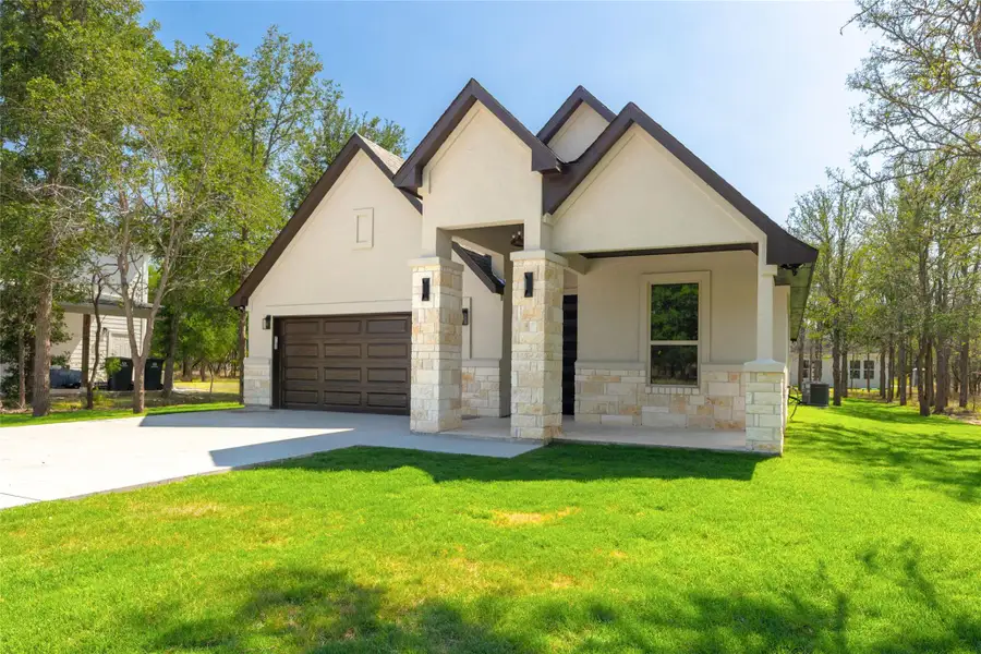 View of front of house featuring stone siding, driveway, a front lawn, stucco siding, and a garage