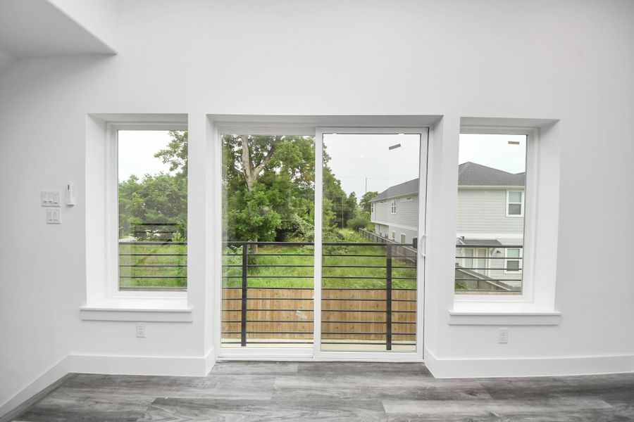 Bright room with large windows and a sliding glass door leading to a balcony. Bright room with large windows and a sliding glass door leading to a balcony.