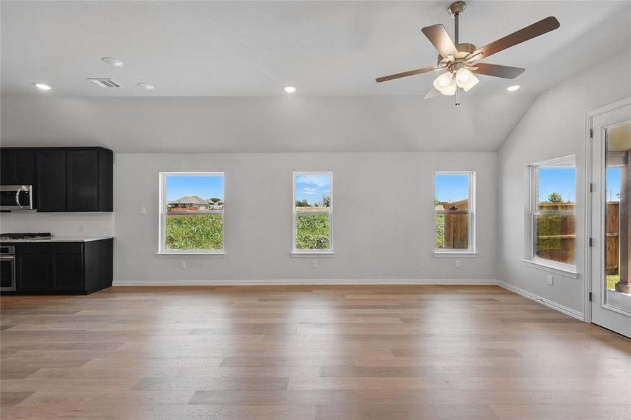 Unfurnished living room with plenty of natural light, lofted ceiling, light wood-type flooring, recessed lighting, and a ceiling fan