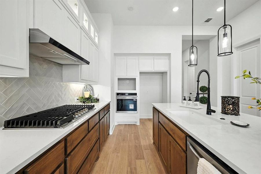 Kitchen featuring light wood-type flooring, white cabinets, light stone countertops, stainless steel appliances, and recessed lighting