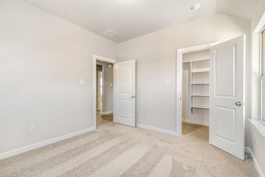 Unfurnished bedroom with light colored carpet and a spacious closet
