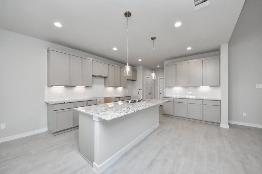 The kitchen is a culinary haven, featuring granite countertops, a tile backsplash, stainless steel appliances, 42” upper cabinets, and undercabinet lighting. Sample photo of completed home with similar floor plan. Actual colors and selections may vary.