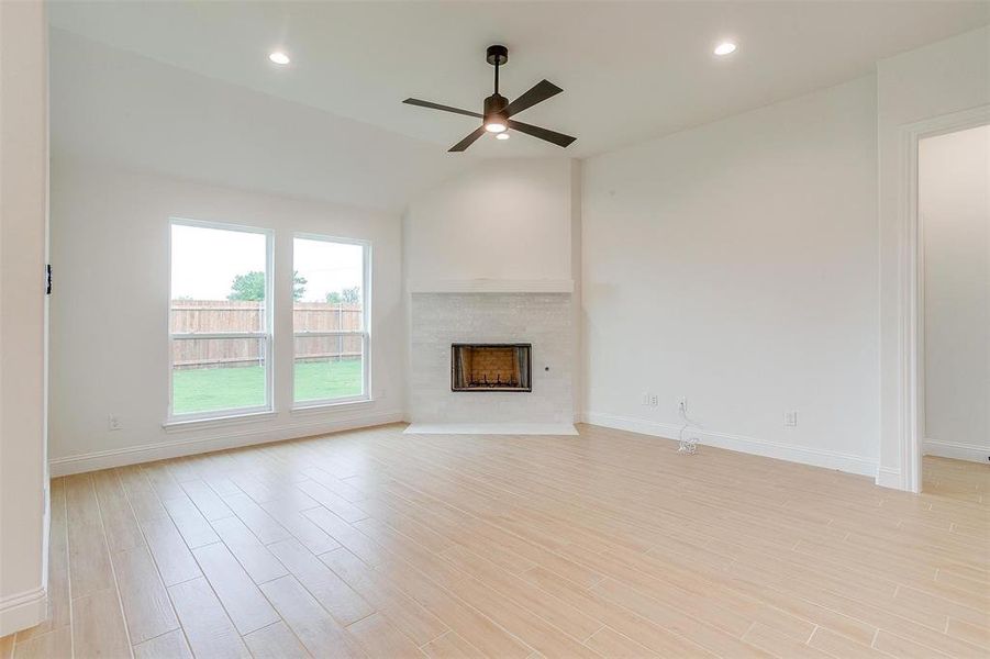 Unfurnished living room with light hardwood / wood-style floors, vaulted ceiling, and ceiling fan