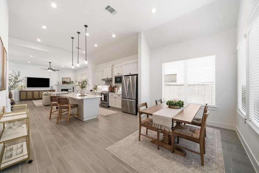 The elegant dining room showcases rich wood-like tile floors and tall ceilings, beautifully accented by recessed lighting and a pre-wire for a future chandelier or ceiling fan. The refined finishes and generous sense of space create an inviting setting for sophisticated entertaining and memorable gatherings.