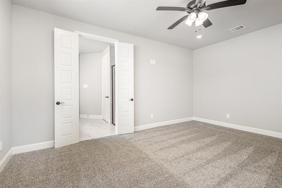 Empty room with light colored carpet and a ceiling fan