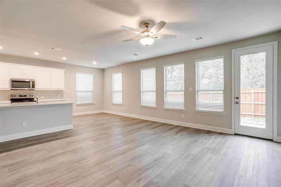 Unfurnished living room featuring ceiling fan, plenty of natural light, and light hardwood / wood-style flooring