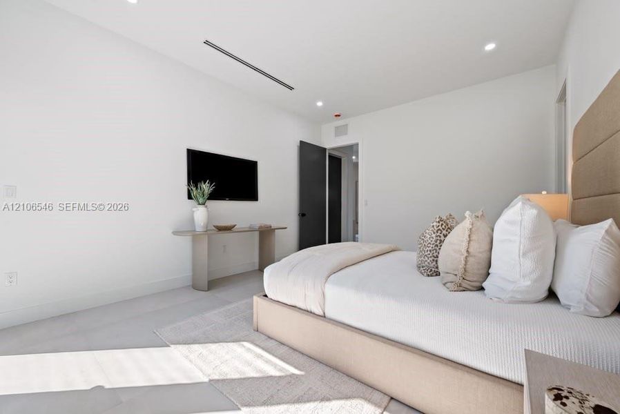 Neutral-toned room featuring recessed lighting, linear architectural ceiling detail, and dark-finished interior door