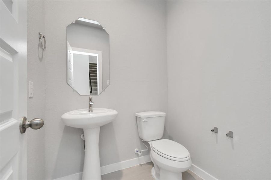 This half bathroom features a stylish pedestal sink, modern hardware, and bright recessed lighting, creating a sleek and inviting space.