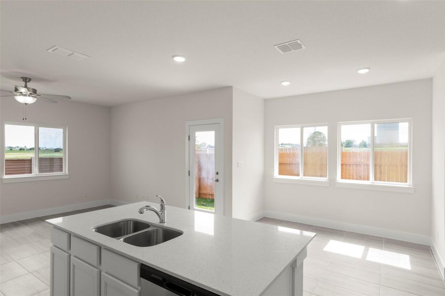Kitchen with light tile patterned flooring, open floor plan, light stone countertops, and a sink
