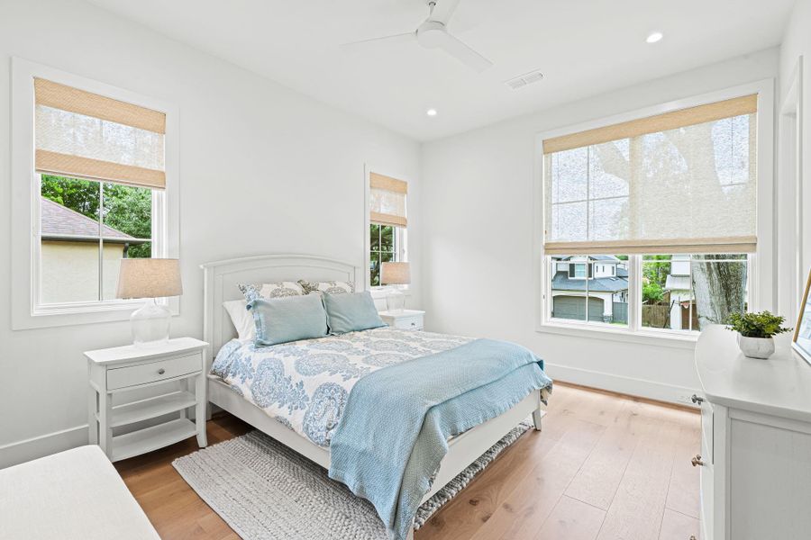 Located upstairs toward the front of the home, this well-proportioned secondary bedroom #1 w/ an en suite bath offers abundant natural light from multiple windows, complemented by custom woven Roman shades. Wide-plank white oak flooring continues throughout, while a walk-in closet w/ built-in shelving & hanging space adds everyday functionality. A linen closet w/ built-in shelving is conveniently located just outside in the hall. Located upstairs toward the front of the home, this well-proportioned secondary bedroom #1 w/ an en suite bath offers abundant natural light from multiple windows, complemented by custom woven Roman shades. Wide-plank white oak flooring continues throughout, while a walk-in closet w/ built-in shelving & hanging space adds everyday functionality. A linen closet w/ built-in shelving is conveniently located just outside in the hall.