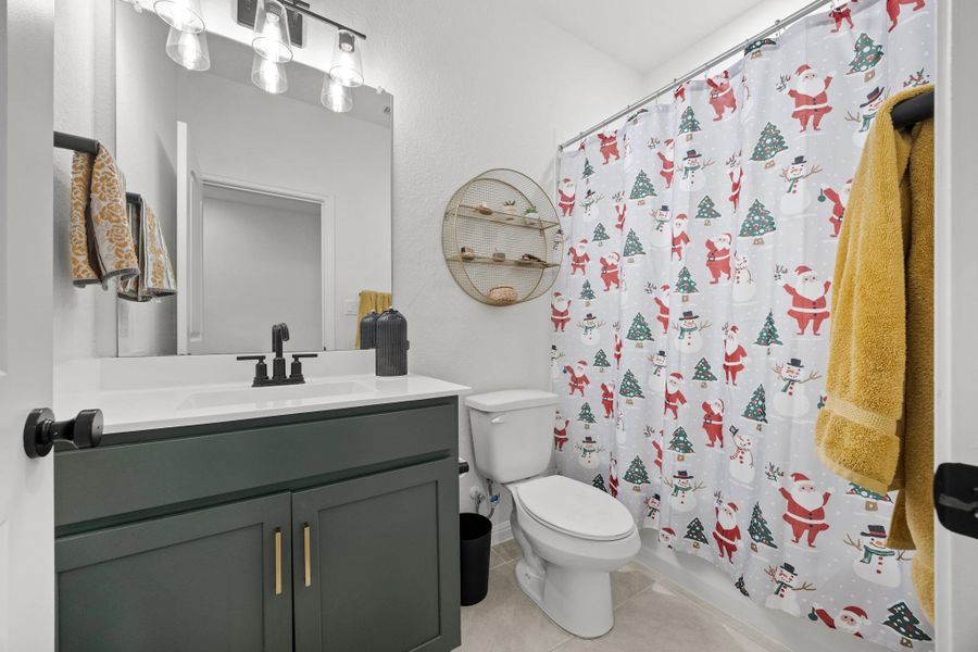 Bathroom featuring a dark green vanity with gold-tone hardware, white countertop, and rectangular mirror