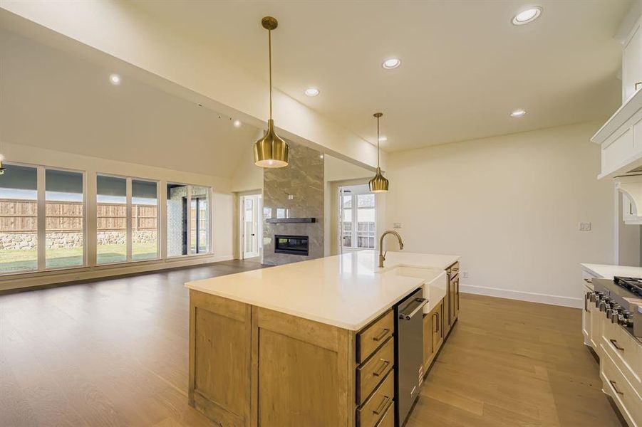 Kitchen with open floor plan, hanging light fixtures, dark wood finished floors, white cabinetry, and a tile fireplace