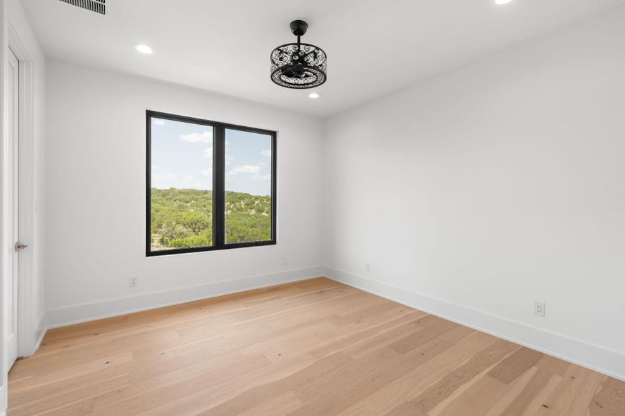 A well-lit room showcasing rich hardwood flooring and expansive window views.