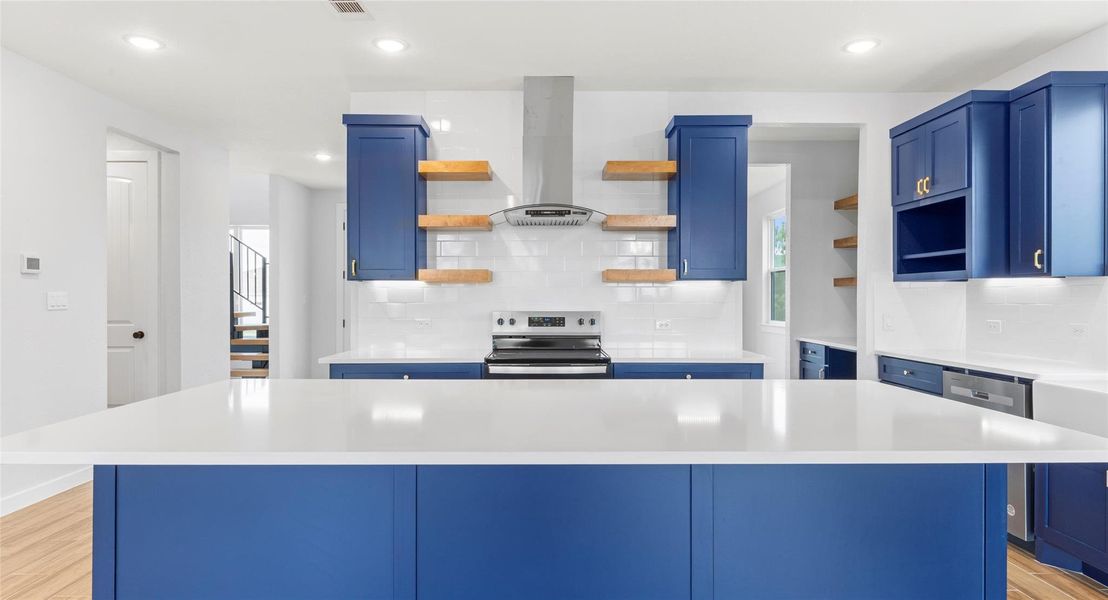 Kitchen with blue cabinetry, open shelves, light wood-style floors, a kitchen island, and stainless steel appliances