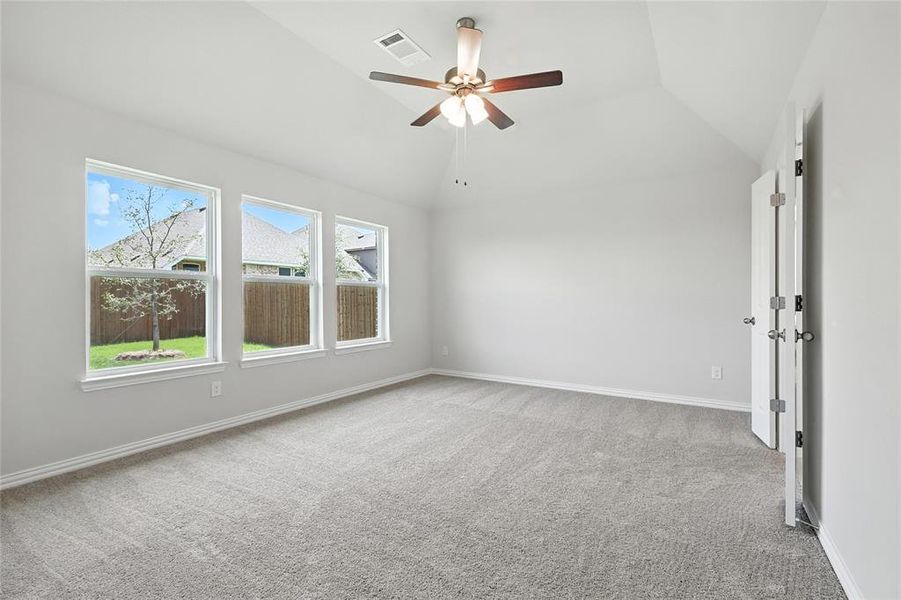 Carpeted spare room with lofted ceiling and a ceiling fan