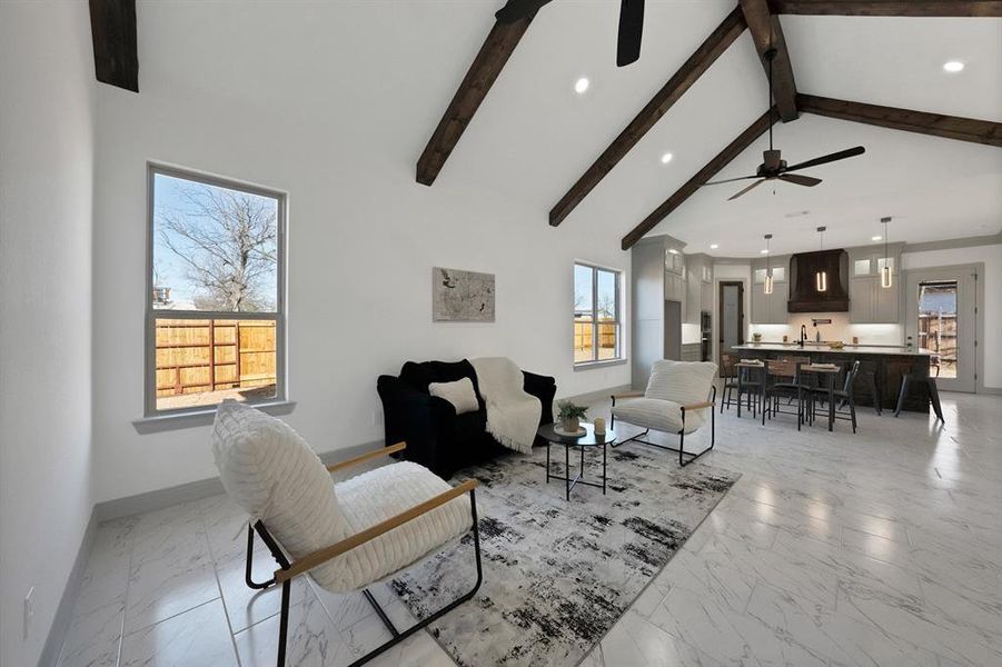 Living area with light marble finish flooring, recessed lighting, high vaulted ceiling, beamed ceiling, and ceiling fan