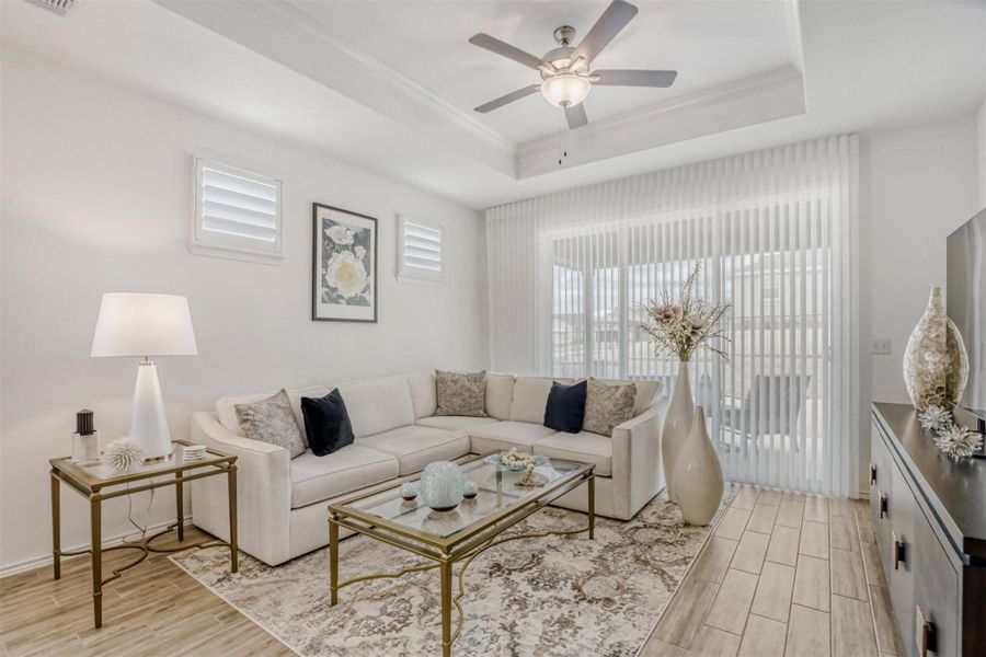 Living room with wood finish floors, ceiling fan, and crown molding
