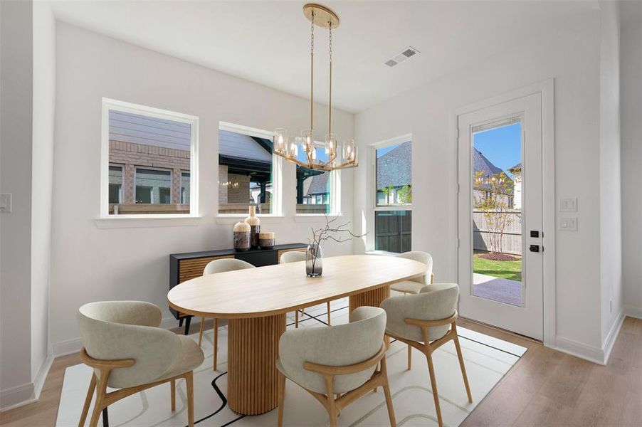 Dining area with light wood-style floors and hanging lights