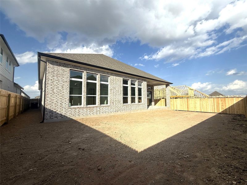 Back of house with brick siding, a fenced backyard, a shingled roof, and a patio area