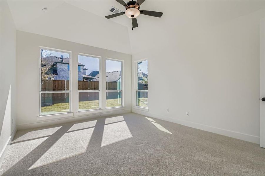 Carpeted empty room with ceiling fan and a high ceiling