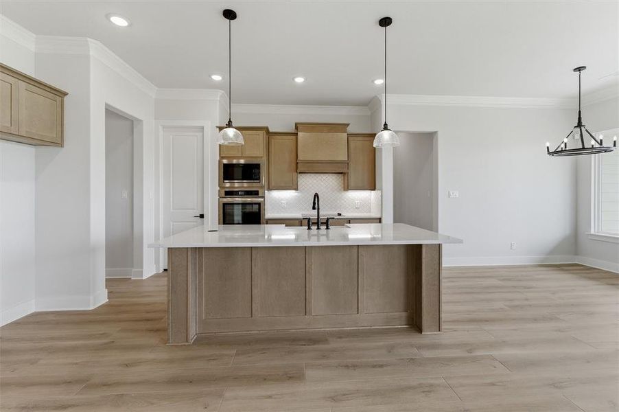 Kitchen featuring a large central island with a light-toned countertop, wood-finish flooring, recessed lighting, and pendant fixtures