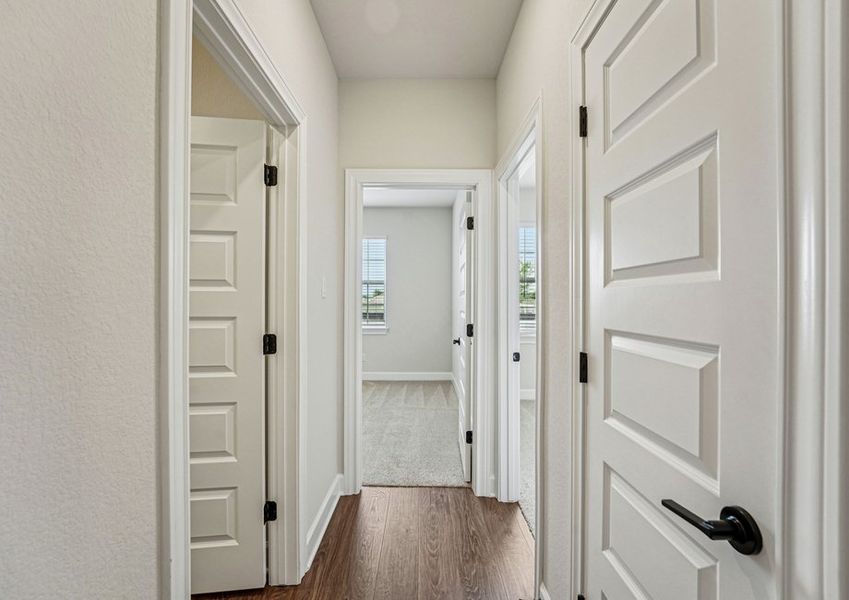Hallway featuring wood-look vinyl flooring and doorways to the secondary bedrooms. Hallway featuring wood-look vinyl flooring and doorways to the secondary bedrooms.
