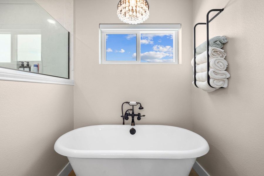 Full bath featuring a freestanding bath, hanging lights, and a textured wall