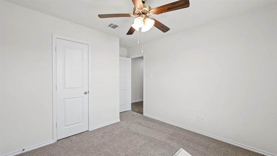 Neutral-toned wall finishes with a ceiling fan, white trim work, and light-colored carpeting