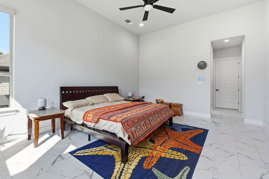A well-lit primary bedroom features ample floor space and a modern ceiling fan for comfort. A well-lit primary bedroom features ample floor space and a modern ceiling fan for comfort.
