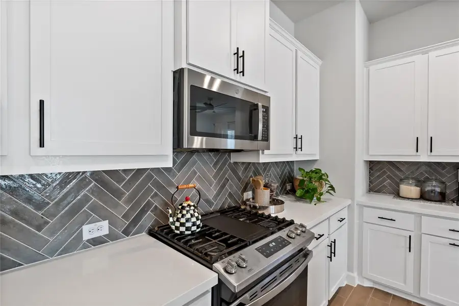 Kitchen with stainless steel appliances, white cabinets, and tasteful backsplash