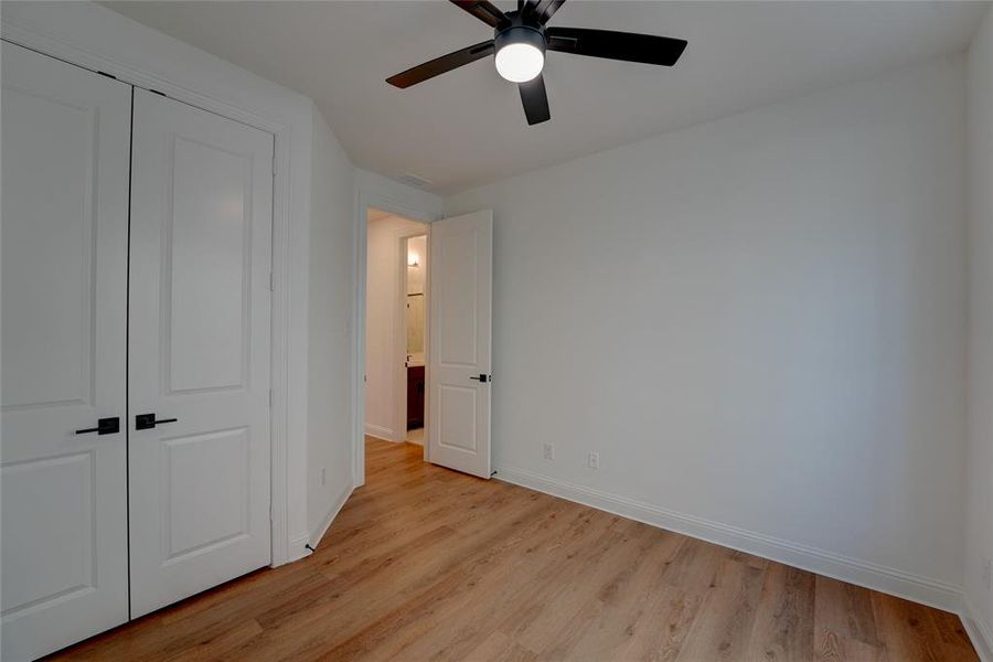 Bedroom with visible vents, baseboards, light wood-style flooring, ceiling fan, and a closet