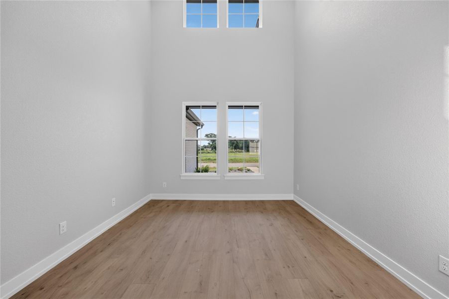 Double-height ceilings and tall windows elevate this versatile space finished with wood-style flooring.