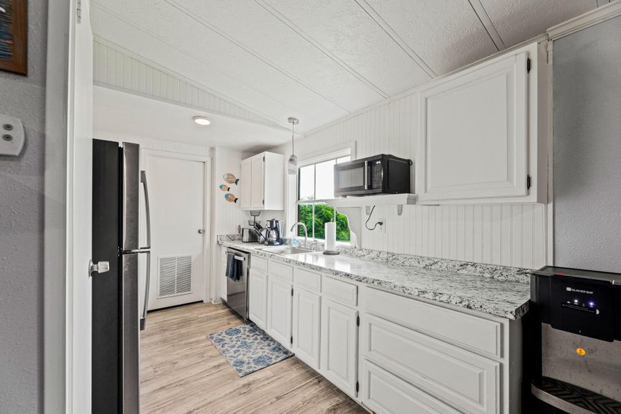 Kitchen featuring white cabinetry, light-toned wood-finish flooring, and a speckled countertop