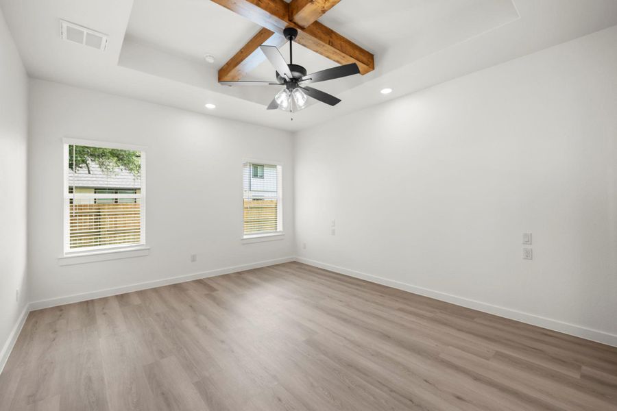A tranquil primary bedroom with warm wood beams and subtle recessed lighting. A tranquil primary bedroom with warm wood beams and subtle recessed lighting.