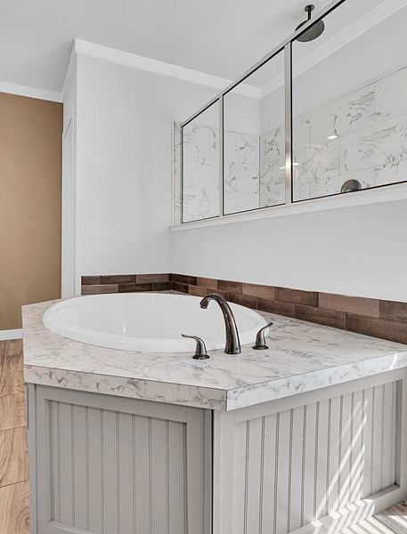 Full bathroom featuring ornamental molding and a garden tub Full bathroom featuring ornamental molding and a garden tub